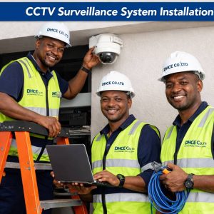Three DHCE CO. LTD technicians installing and configuring a CCTV surveillance system while smiling and working professionally on site.