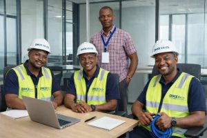 DHCE Co. Ltd CCTV surveillance installation team with supervisor in office planning security system deployment, wearing safety vests and helmets.