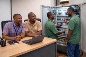 DHCE engineers installing and configuring GSM signal booster equipment and electrical control panel to improve mobile network coverage in an office environment