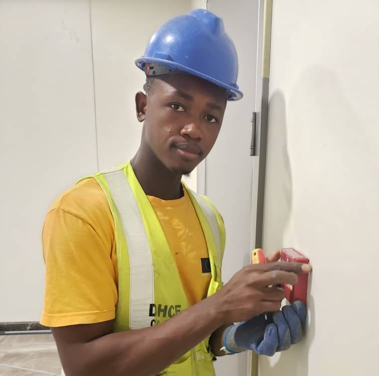 Technician installing emergency break glass call point as part of fire alarm system installation in a commercial building.