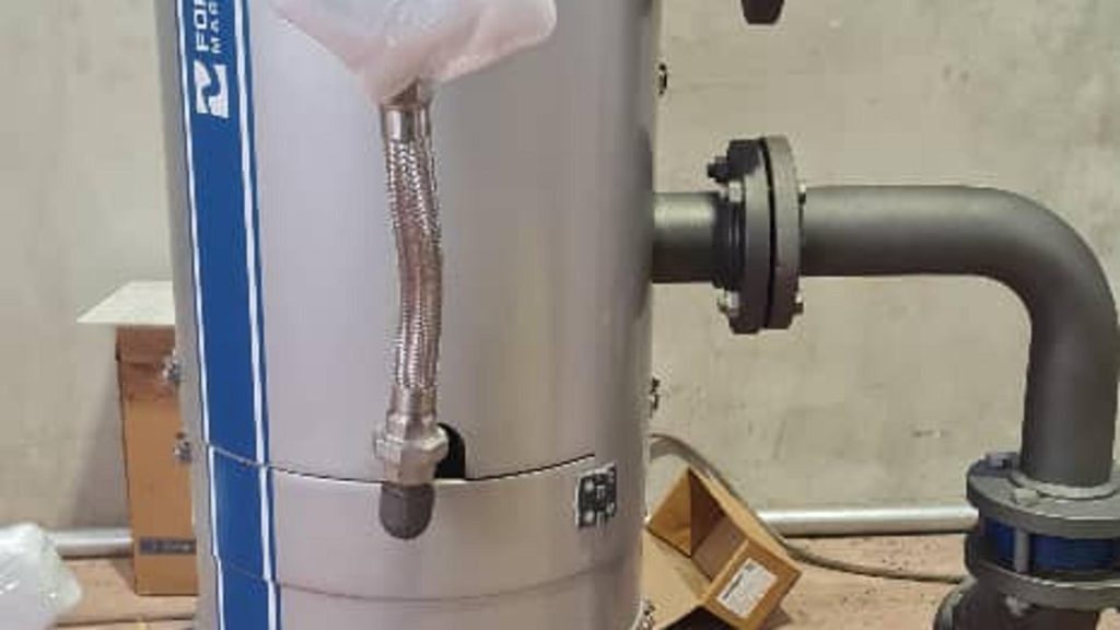 Vertical industrial pipeline strainer used for filtering debris from fluid pipelines in a mechanical processing plant.